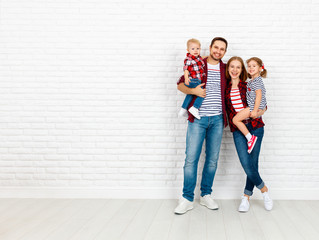 Happy family mother, father, son, daughter on a white blank wall