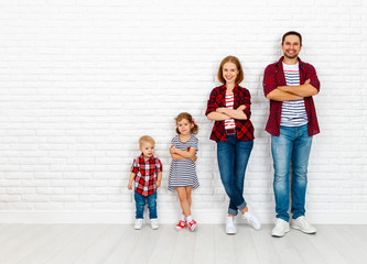Happy family mother, father, son, daughter on a white blank wall
