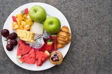 Top view of fruit plate by over concrete floor background. Exotic summer diet. Tropical beach lifestyle.
