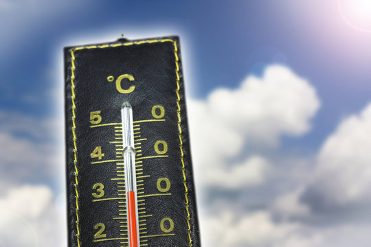 Learher thermometer with blue sky, clouds and lens flare