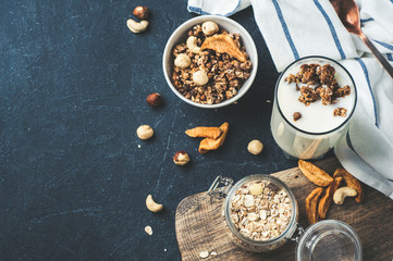 Yoghurt, muesli, nuts and dried fruits on a wooden Board over dark stone background. Diet, weight loss or healthy eating concept. Copy space for text or design