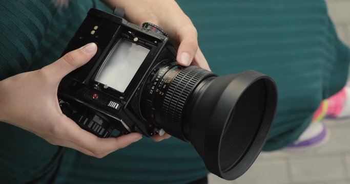 Old medium format camera in the hands of a hipster girl, close-up, film camera