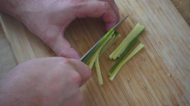 Cutting a green onion on a wooden board. Close Up. Selective Focus