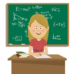 Female teacher sitting at table in classroom next to blackboard