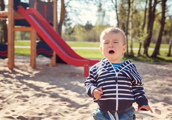 Little boy playing on playground and crying