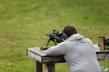 The sniper rifles his rifle and prepares for a shot in the forest on the table.