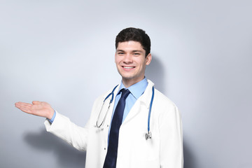 Handsome young doctor on light background