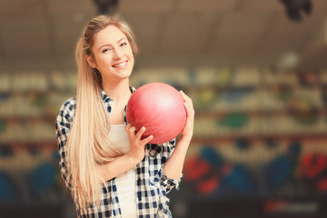 Fototapeta na wymiar Beautiful young woman with ball in bowling club