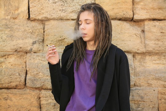 Young Boy Smoking Weed On Stone Wall Background