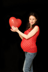 Fototapeta na wymiar Cute pregnant girl with red heart balloon on a black background