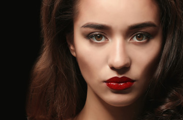 Fototapeta premium Portrait of beautiful woman with red lips on dark background