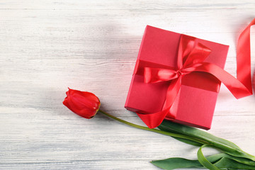 Beautiful tulip and giftbox on light wooden background