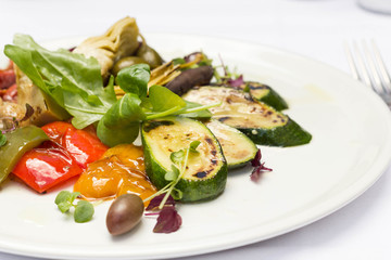 Colorful roasted vegetables on white plate served in restaurant.