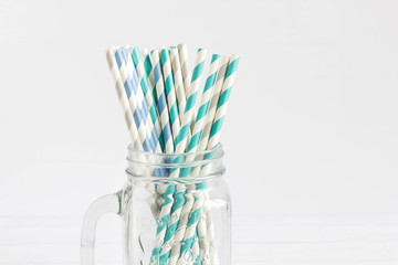 Paper straws in purple, and green color placed on a trendy mason jar. Isolated shoot of party and wedding equipment. Collection of colorful straws