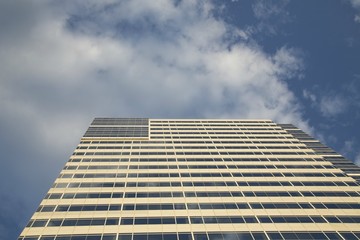 Dramatic Straight Up Frontal Upward Skyward View Exterior Modern Reflective Glass Facade Skyscraper Tall Building in Business District Downtown Area, Against Blue Sky White Clouds, Daytime, West Coast