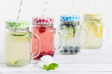 Sugar free and gluten free homemade drinks with trendy mason jars and colorful straws placed on white wooden board.