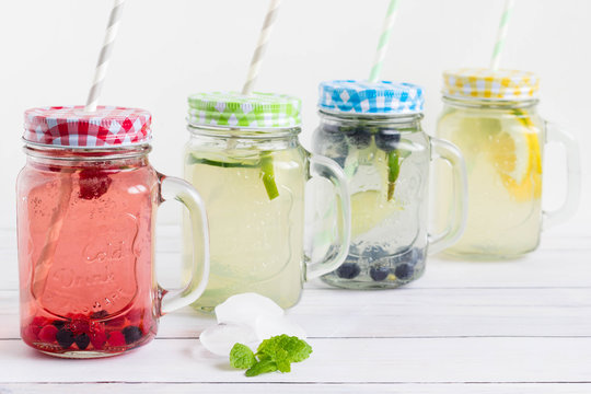 Sugar free and gluten free homemade drinks with trendy mason jars and colorful straws placed on white wooden board.