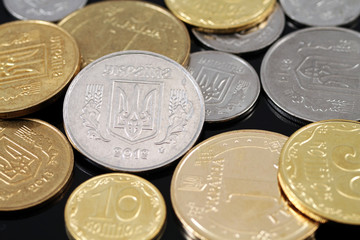 A close up image of assorted Ukrainian coins on a black background