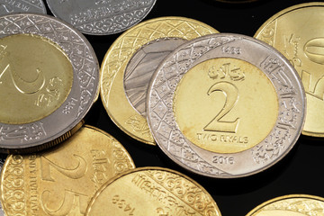 A close up image of assorted Saudi Arabian coins on a black background