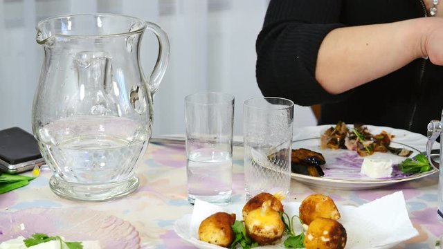 Woman hands pouring raki and adding ice into the glass. Close up. In the bottle raki is absolutely clear but when you mix it with ice or water for drinking it changes color and turns into milky white.