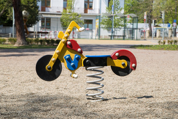 Children's swing in the form of a motorcycle. Element from the playground