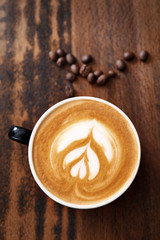 Cup of coffee with latte art on wooden background