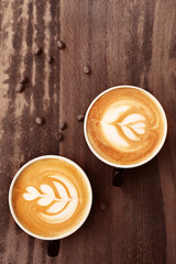 Cups of coffee with latte art on wooden background