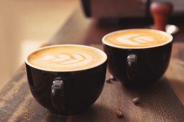Cups of coffee with latte art on wooden background