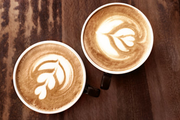 Cups of coffee with latte art on wooden background