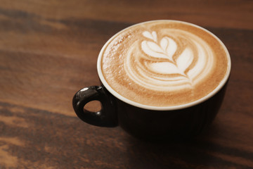 Cup of coffee with latte art on wooden background