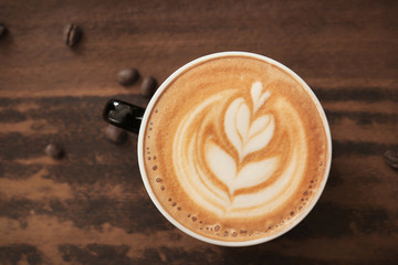 Cup of coffee with latte art on wooden background