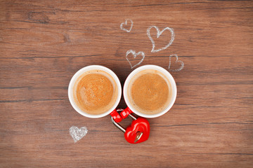 Cups of coffee with hearts on wooden table