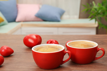Cups of coffee with hearts on wooden table
