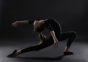 Young girl doing gymnastics on dark background