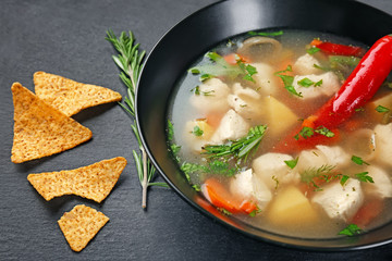 Plate with chicken soup and chili pepper on table