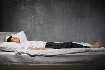 Young man sleeping in bed - obrazy, fototapety, plakaty