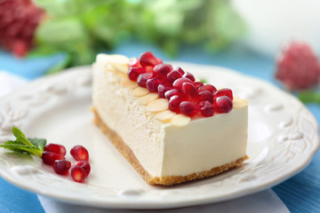 Tasty cheesecake slice with pomegranate on plate
