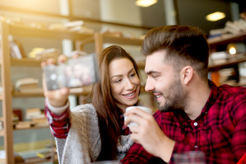 Happy smiling couple taking a selfie with smart phone. A girl tenderly looking at her boy.