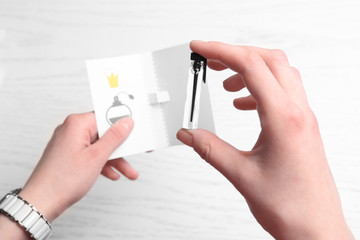 Female hand holding perfume sample on light background