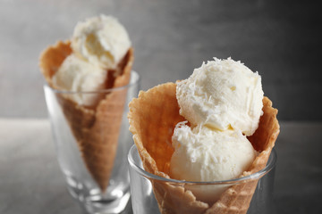 Glasses with waffle cones and balls of coconut ice cream on grunge background