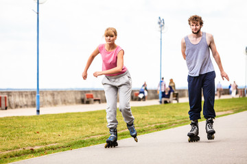 Two people race together riding rollerblades.