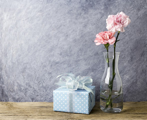 Mothers day concept of pink carnation flowers in clear bottle and gift box