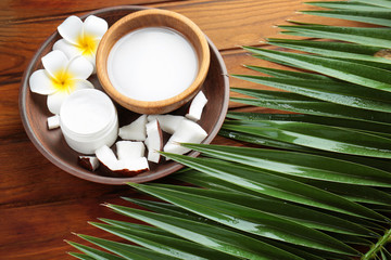 Composition with coconut milk and exotic flowers on wooden background
