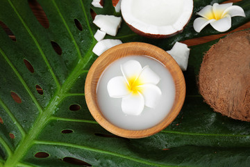 Composition with coconut milk and exotic flowers on palm leaf