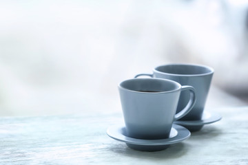 Cups with hot tea on wooden table against blurred background