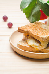 Toast breads with fried egg and grapes on wooden table background.