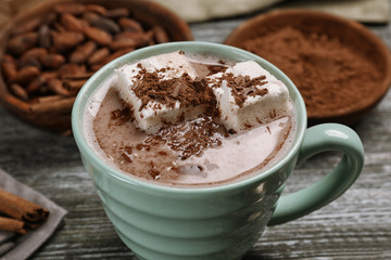 Cup with tasty cocoa drink and marshmallow on wooden table, closeup
