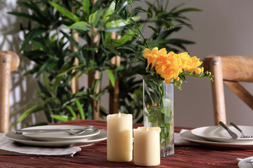 Beautiful festive table setting and vase with flowers in light room