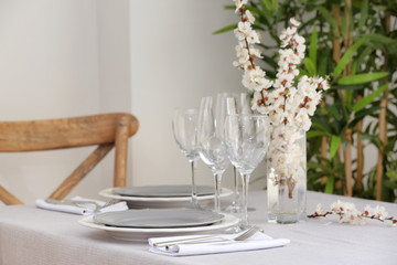 Table setting with vase of flowers in light room