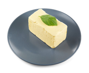 Plate with butter and basil leaf on white background, closeup